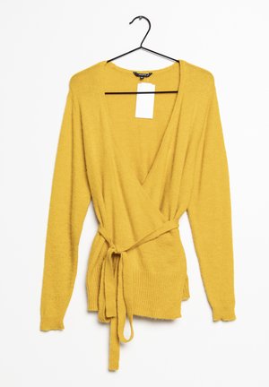 Gelber Wickelcardigan mit langen Ärmeln, tiefem V-Ausschnitt, Bindegürtel in der Taille und geripptem Saum. Hergestellt aus weichem, strukturiertem Material.