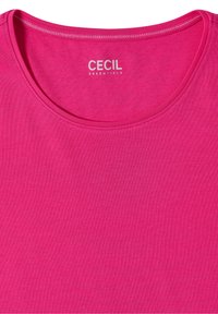 T-shirt rose vif à col rond avec « CECIL ESSENTIALS » imprimé en blanc à l'intérieur du col.