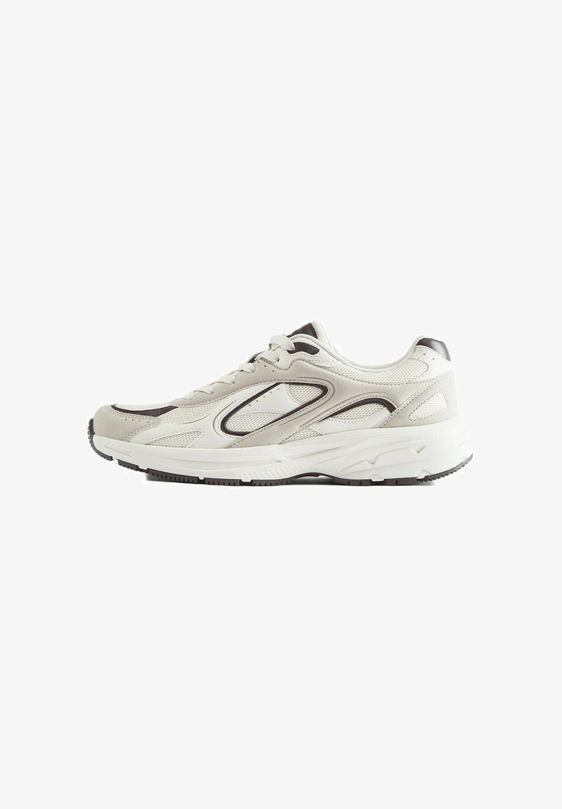 Baskets blanches et gris clair avec panneaux en mesh et daim, fermeture à lacets à l’avant et semelle épaisse texturée, vues de profil.