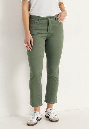 Groene katoenen mix cropped jeans met een middelhoge taille, voorzien van een knoopsluiting, vijf zakken en een rechte pasvorm. Draagt met witte sneakers.