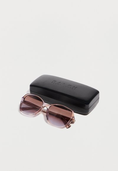 Διάφανα ροζ γυαλιά ηλίου με καφέ φακούς, τοποθετημένα δίπλα σε μαύρη θήκη γυαλιών με το λογότυπο Ralph Lauren, σε λευκό φόντο.