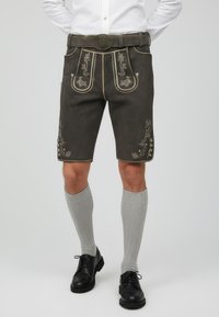 Siyah lederhosen dengan bordir emas yang rumit dan aksen, dilengkapi dengan saku depan, pinggang berpita, dan panjang hingga lutut. Dipadukan dengan kaus kaki abu-abu.
