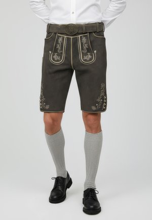 Siyah lederhosen dengan bordir emas yang rumit dan aksen, dilengkapi dengan saku depan, pinggang berpita, dan panjang hingga lutut. Dipadukan dengan kaus kaki abu-abu.