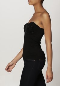 Haut noir bustier avec une coupe ajustée et des accents subtils scintillants sur le corsage, fabriqué en tissu extensible lisse.