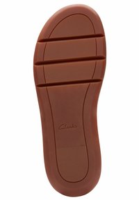 Suola in gomma con scanalature orizzontali e verticali. Colore marrone con logo "Clarks" impresso. Texture liscia, design a punta rotonda.