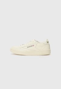 Hvite skinnesneakers med teksturert overflate, med rund tå, flate lisser, og Reebok-logo på siden og hælen.