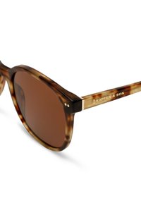 Ruske tortoiseshell sunčane naočale s okruglim okvirom, smešnim lećama i zlatnim detaljima. Sadrži brend "Kapten & Son" na dršku.