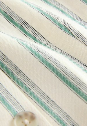 Baumwollstoff mit vertikalen Streifen in Grün und Marineblau, auf einem beigen Hintergrund; umfasst ein abgerundetes, transparentes Knopfdetail.