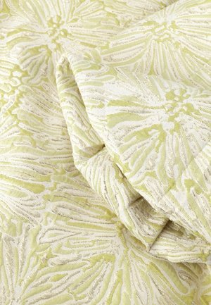 Tissu vert clair et crème plié, présentant des motifs floraux texturés avec des détails en relief et complexes.