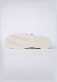 Suela de zapato plana con un patrón texturizado, que presenta un material de goma beige claro y ranuras horizontales para mejorar la tracción.