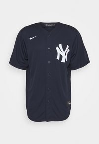 Laivastonsininen baseball-paita, valmistettu synteettisestä kankaasta, jossa on napitettava etuosa ja suuri valkoinen New York Yankeesin logo vasemmassa rinnassa.