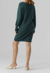Stickad teal klänning med långa ärmar och en lös passform, som slutar ovanför knäet. Matchad med beiga klackmules. Mjuk textur.