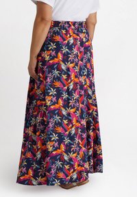 Gonna lunga e fluente realizzata in tessuto con uno sfondo blu scuro. Presenta un vivace motivo floreale e di uccelli in tonalità di rosa, arancione e blu. Vita elasticizzata.