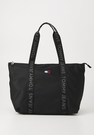 Black tote bag made of durable fabric, featuring dual handles with "TOMMY JEANS" text, zip closure, and a small logo patch at front.