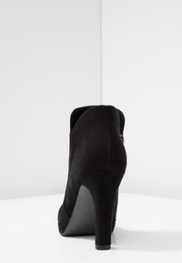 Schwarze Wildleder-Ankle Boots mit hohem Absatz, abgerundeter Spitze, glatter Textur und seitlichem Reißverschluss. Mit einem stabilen Stiletto-Absatz für mehr Höhe.