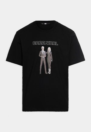 Black t-shirt with "CARA KARL" text and graphic of two figures wearing suits, one with sunglasses, on the front center.