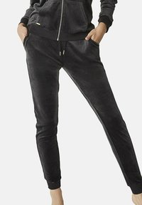 Zwarte velours joggers met een slim fit, elastische tailleband en verlaagde enkels. Steekzakken aan de zijkanten; gladde textuur met een lichte glans.