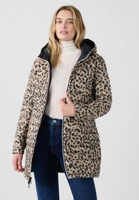 Chaqueta de plumas con estampado de leopardo en beige y marrón, con capucha negra, cierre de cremallera y textura acanalada. Combinada con un cuello vuelto blanco.