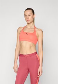 Puma sportski grudnjak u svijetloj koralj boji s tankim podesivim trakama i crnim logom. Odgovarajuće visoke tajice u dubokoj ružičastoj boji s koralj akcentima.