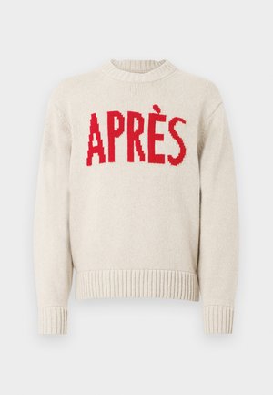 Beżowy, dziergany sweter z prążkowanymi mankietami i dołem, ozdobiony dużym, czerwonym napisem "APRÈS" na klatce piersiowej.