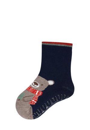Navyblaue Socke für Kinder mit einem braunen Bären, der einen roten Schal trägt und einen grünen Weihnachtsbaum hält. Die Sohle verfügt über eine rutschfeste Beschichtung.