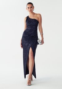 Viestura krāsas vakarkleita ar vienu plecu un spīdumiem. Kleitai ir sānu šķēlums un saskrāpētas detaļas. Pievienotas sudraba rotaslietas un siksniņkurpes ar papēdi.