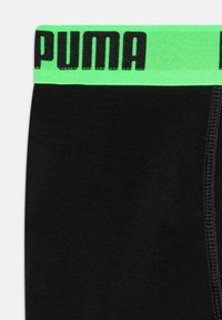 Crne bokserice s zelenim elastičnim pojasom na kojem je u debelim crnim slovima ispisano "PUMA". Glatka tkanina s ravnim šavovima.