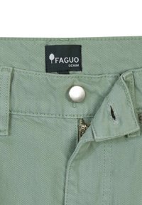 Lichtgroene denim broek heeft een ritssluiting en knoopsluiting, met een merklabel dat "FAGUO DENIM" leest en een klein scheurtje.