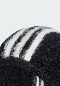Schwarze Kappe aus strukturiertem Stoff, mit drei auffälligen weißen Streifen auf der Oberseite, die ihr sportliches Design und ihre Weichheit betonen.