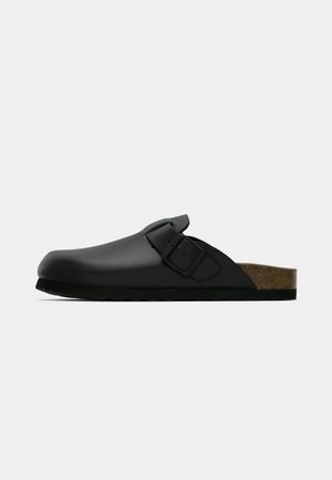 Black slip-on clog made of smooth material, featuring a single adjustable buckle and a cork footbed with a textured sole.