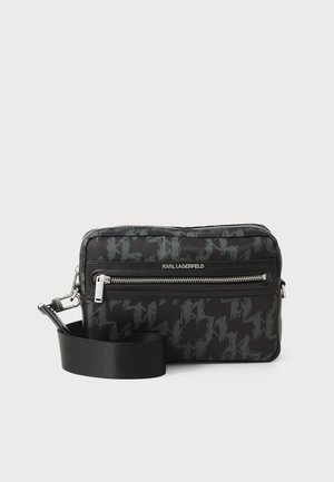 Schwarze Stofftasche mit Hahnentritt-Muster, Reißverschlussfächern und abnehmbarem Schulterriemen. Silberne Beschläge und Markenlogo auf der Vorderseite.