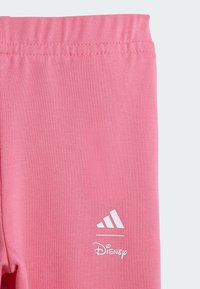 Rosa idrottsleggings med en mjuk textur, med Adidas-logotyp och Disney-märke i vitt. Elastisk midja för komfort.