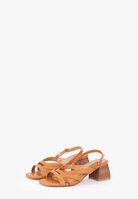 Sandali in pelle color cuoio con design a slingback, con punta aperta e cinturini intrecciati. Tacco a blocco con texture effetto legno. Accento con fibbia.