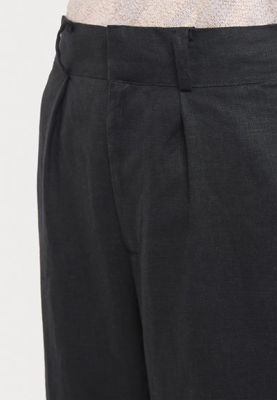 Črne lanene hlače z pregibno sprednjo stranjo, prilagojenim pasom in čistimi linijami, idealne za sproščene ali formalne priložnosti.