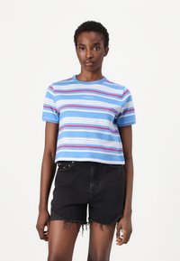 Korte lichtblauwe T-shirt met horizontale strepen in roze en wit; korte mouwen; gecombineerd met hooggesneden zwarte denim short.