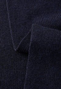 Tissu tricoté bleu marine avec une texture côtelée. Le design présente des rayures alternées, montrant une épaisseur variable et une apparence douce et chaleureuse.