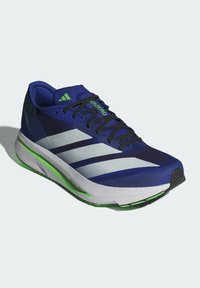 Blue running shoes with a textured upper, silver stripes, and green accents. Lightweight design, featuring a cushioned sole and a streamlined shape.