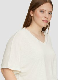 Witte v-hals t-shirt met korte, iets verlengde mouwen. Gemaakt van een gestructureerde, lichte stof met een losse pasvorm.