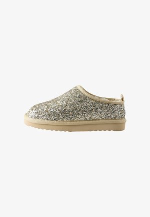 Slip-On-Schuh mit beiger Gummisohle und Obermaterial, das mit silbernem und goldenem Glitzer bedeckt ist, seitlich auf weißem Hintergrund gezeigt.