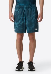 Men's athletic shorts in a blue tie-dye pattern, made from lightweight material, featuring an elastic waistband and logo detail on the hem.