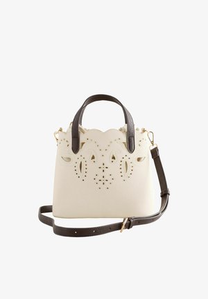 Cremefarbene Handtasche mit dunkelbraunen Griffen und Riemen, mit filigranen ausgeschnittenen Blumenmustern auf der Vorderseite und gezacktem oberen Rand.