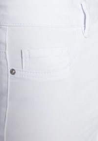 Witte denim jeans met een klein voorvak, subtiele textuur en ton-sur-ton stiksels. De stof lijkt glad met een strakke afwerking.
