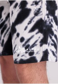 Crno-bijeli šorts s tie-dye uzorkom od pamuka, s glatkom teksturom i logotipom "ALPHA INDUSTRIES" na donjem dijelu noge.