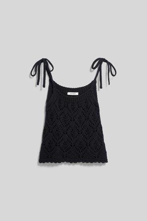 Black knitted sleeveless top with diamond lace pattern and tie straps on a light gray background.