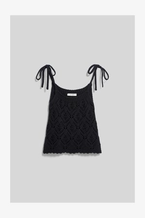 Black knitted sleeveless top with diamond lace pattern and tie straps on a light gray background.