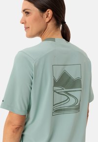 T-shirt de sport en tissu respirant vert menthe avec des manches courtes, présentant un graphique de montagnes et d'une route sinueuse au dos.