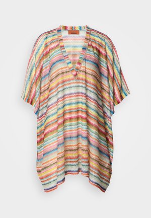 Poncho ampio con scollo a V e maniche corte, decorato con un motivo a zigzag colorato che mescola tonalità arcobaleno su uno sfondo di tessuto chiaro.