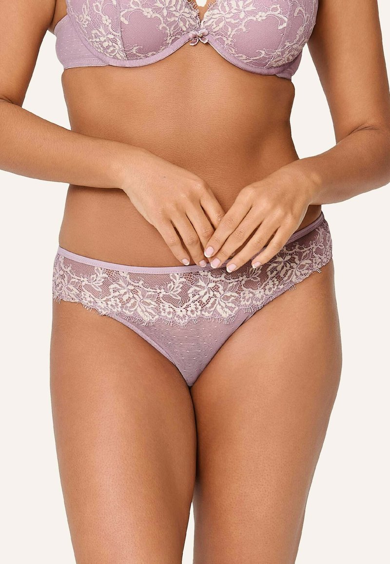 Prádlo v jemnej fialovej farbe so čipkovým lemovaním obsahuje ľahko polstrovanú podprsenku a zodpovedajúce stringy s bodkovanou textúrou a kvetinovými akcentmi.