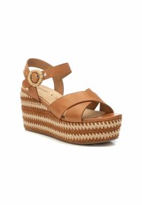 Sandalette con zeppa in pelle marrone, con cinturini incrociati, accentata da una fibbia rotonda e una piattaforma in juta intrecciata con strisce alternate color marrone chiaro e beige.