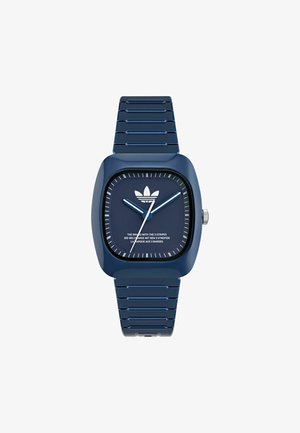 Modra plastična ura s kvadratno ohišjem, teksturiranim paščkom in belo številčnico, ki vsebuje logotip s tremi črtami ter oznake ur.